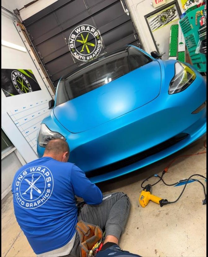 Installer applying vinyl film to a Tesla during a colour change wrap